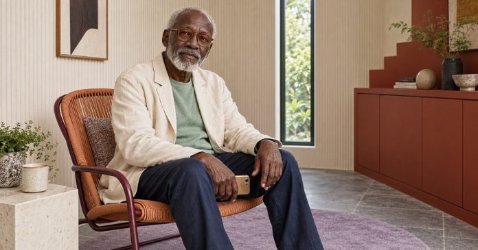 A mature man pausing with a phone resting near his lap.