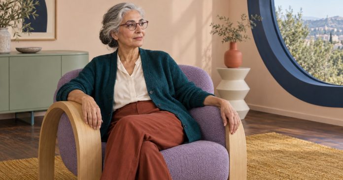 A woman sitting thoughtfully in a lavender armchair in a bright room
