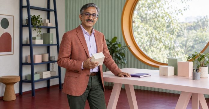 A man examining a plain product sample box in a small studio