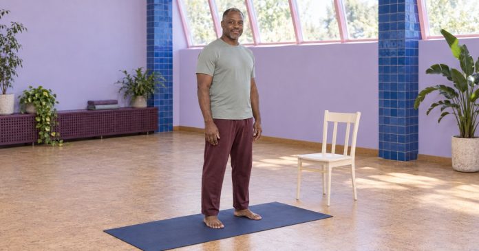 Yoga practice at a manageable pace An adult man standing comfortably on a yoga mat in a bright studio