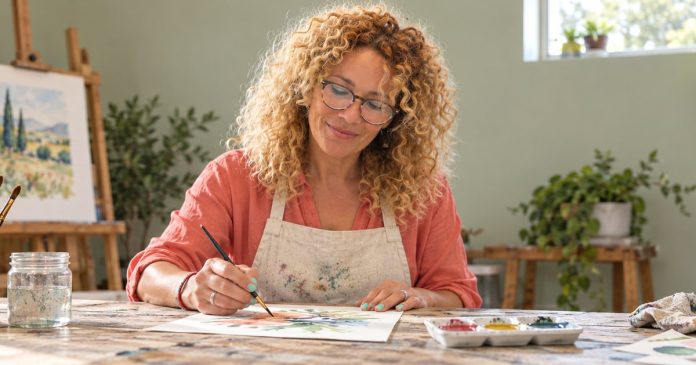 number-3-distinct-model-20261014 A woman expressing her creativity through watercolor painting in a bright art studio.